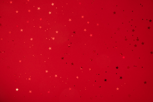 Shining stars, sparkles, confetti on red background. Festive holiday background. Christmas. Wedding. Birthday. Happy woman's day. Mothers Day. Valentine's Day. Flat lay, top view