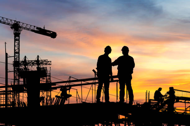 istock Silhouette of Engineer and worker checking project at building site background, construction site at sunset in evening time. 1284846138
