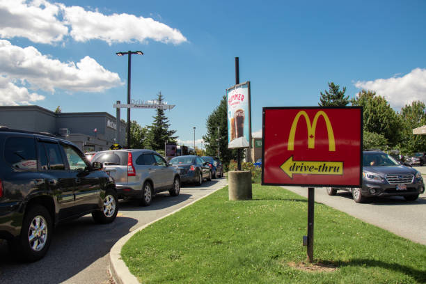 voitures faisant la queue pour commander de la nourriture en utilisant des installations drive-thru au restaurant mcdonald’s local - brand name yellow red business photos et images de collection