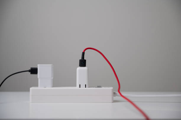 電気アダプターのスマートフォンは、複数のソケットに接続します。家の中の電気機器、電線および電源ストリップ。電気エネルギーを節約するアースアワー。 - mobile phone charging power plug adapter ストックフォトと画像