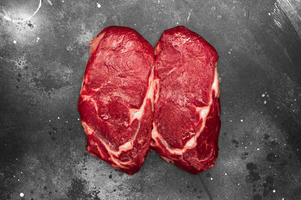 istock Ribeye fresh raw beef steak on dark background. Top view flat lay 1284853526