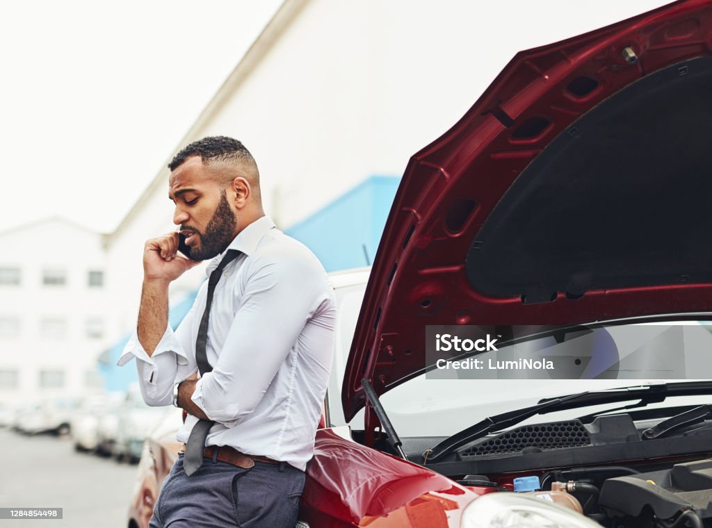 I've been holding on the line for an hour already Shot of a man calling roadside assistance after breaking down Car Accident Stock Photo
