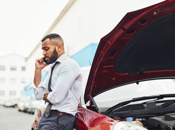 I've been holding on the line for an hour already Shot of a man calling roadside assistance after breaking down car accident photos stock pictures, royalty-free photos & images