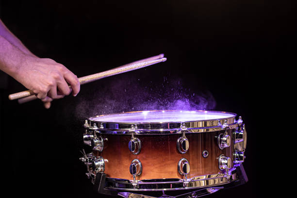 istock Drum sticks hitting snare drum with splashing water on black background under studio lighting. 1284856475