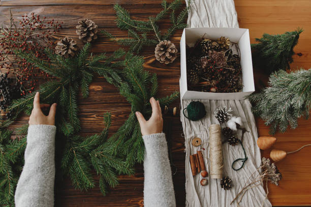 istock Making rustic christmas wreath flat lay. Hands holding green fir branches on wooden table 1284856805