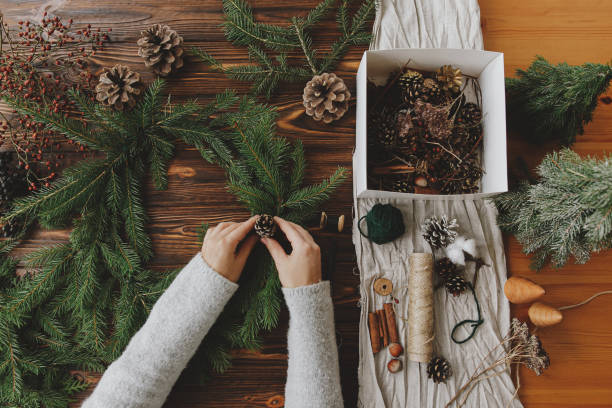 istock Hands holding pine cone and green fir branches on wooden table, making rustic christmas wreath 1284856918