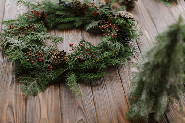 istock Modern christmas wreath with berries, pine cones, natural tree decorations on rustic background 1284857914
