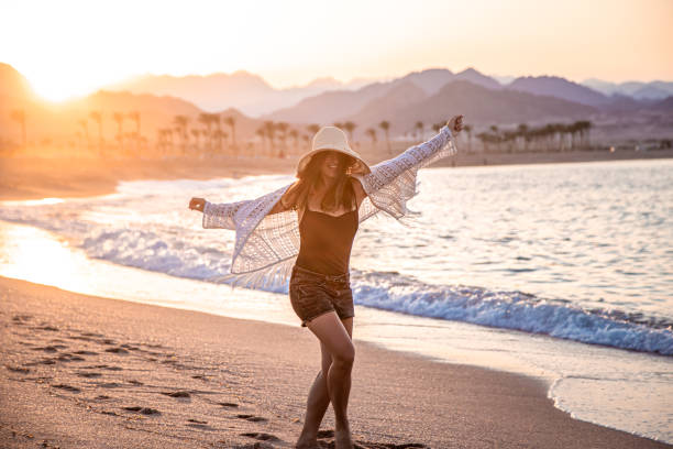 istock Woman at sunset on the beach in a hat. 1284858821