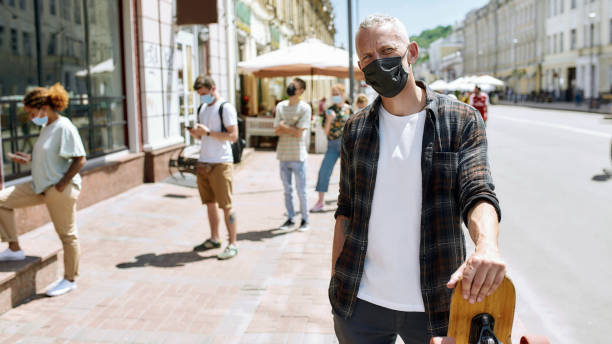 istock Middle aged man wearing mask holding a longboard and looking at camera 1284858986