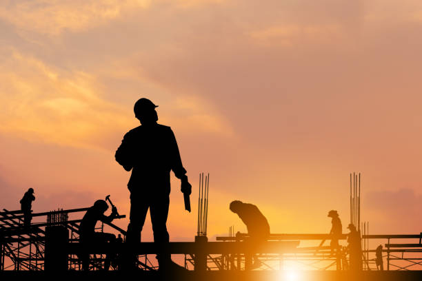 istock Silhouette of Engineer and worker checking project at building site background, construction site at sunset in evening time. 1284861205