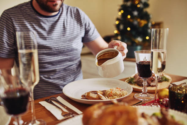 Calories don't count at Christmas Shot of an unrecognisable man pouring gravy onto his food at Christmas lunch dont eat meat stock pictures, royalty-free photos & images