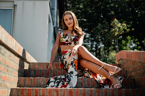 beautiful young elegant woman wearing a fashionable floral pattern summer dress on a sunny summer day outdoors