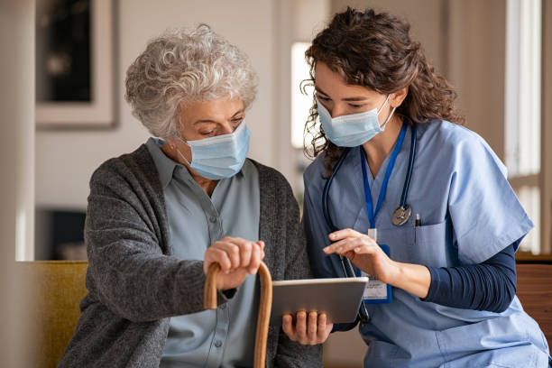 Senior woman and nurse using digital tablet at home during consult