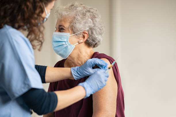 先輩女性にコビッドワクチンを与える医師 - コロナウイルス 写真 ストックフォトと画像