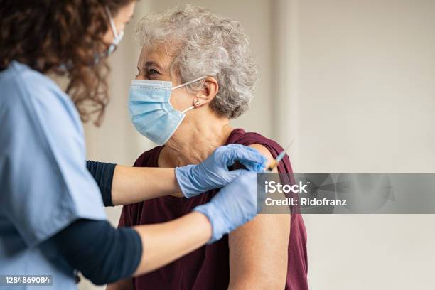 Doctor Giving Covid Vaccine To Senior Woman Stock Photo - Download Image Now - Vaccination, COVID-19 Vaccine, Senior Adult