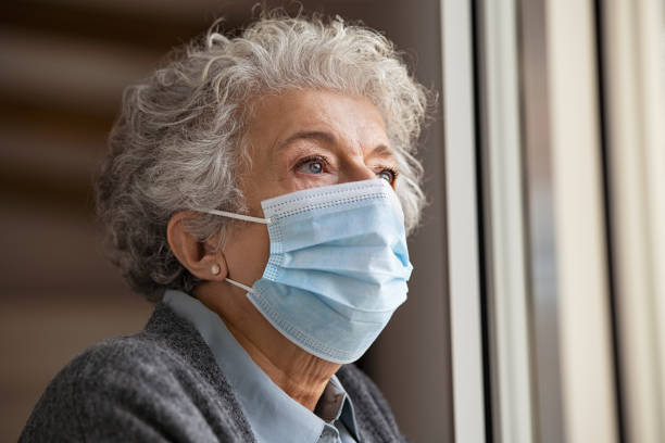 istock Sad senior woman wearing face protective mask at home 1284869086