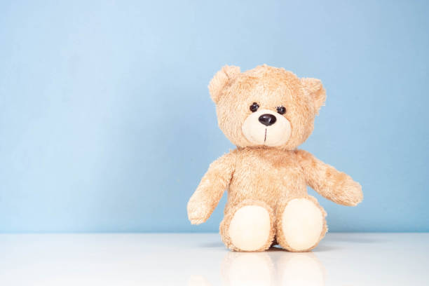 istock Teddy Bear sitting on a white table and blue background. 1284869138