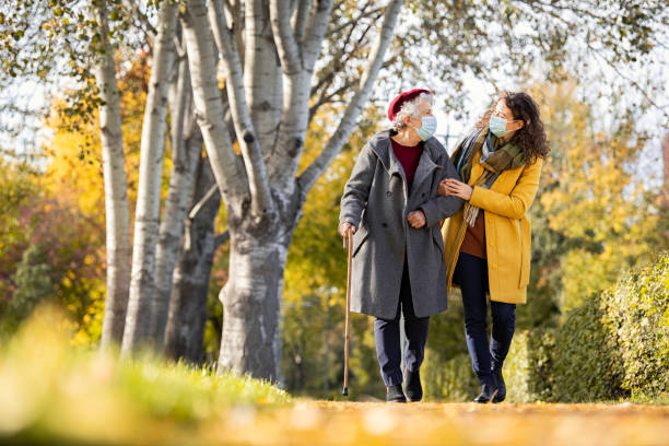 старшая женщина с девушкой в маске в парке - senior adult winter senior women daughter стоковые фото и изображения