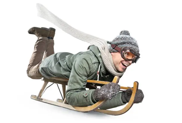 A smiling man lying on a sled. Isolated on a white background.