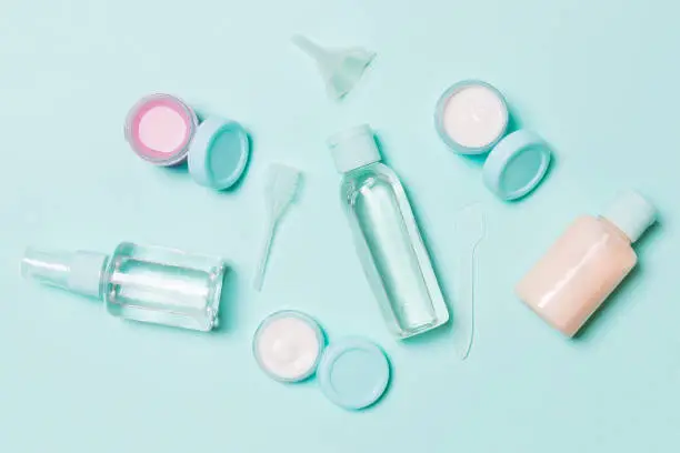 Set of travel size cosmetic bottles on blue background. Flat lay of cream jars. Top view of bodycare style concept.