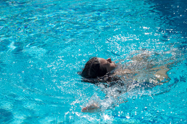 istock Woman Swimming in a Swimming Pool with Sunlight 1284880672