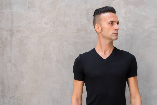 Portrait of handsome young Italian man with undercut wearing black t-shirt and thinking Portrait of handsome young confident Italian man with undercut half shaved hairstyle stock pictures, royalty-free photos & images