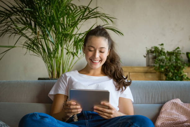 istock Cheerful young woman using digital tablet at home 1284881975