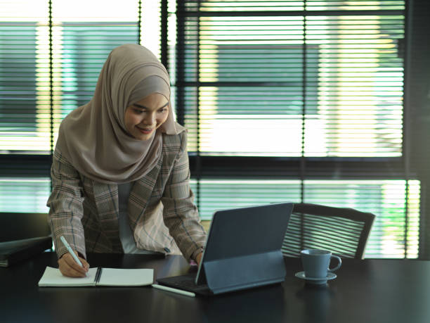 istock Muslim businesswoman working with digital tablet while standing in office room 1284883496