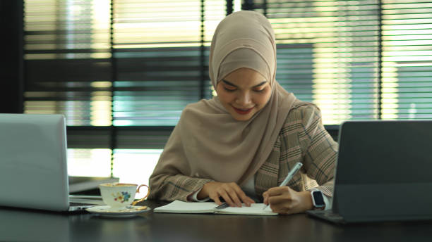 istock Muslim businesswoman writing on notebook while working in office room 1284883785