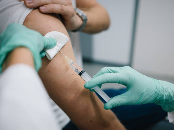 jeune médecin administrant une dose de vaccin - administering photos et images de collection