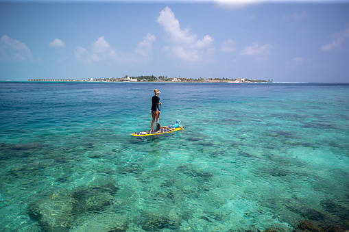 Stand Up Paddling over a tropical reef in the Maldives