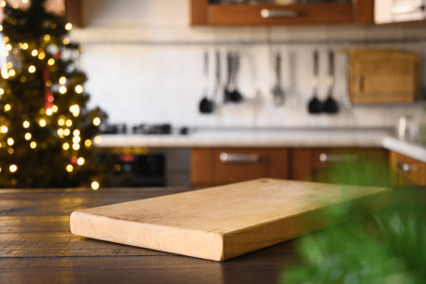 istock Wooden tabletop with cutting board and blurred modern kitchen with Christmas tree. 1284888550