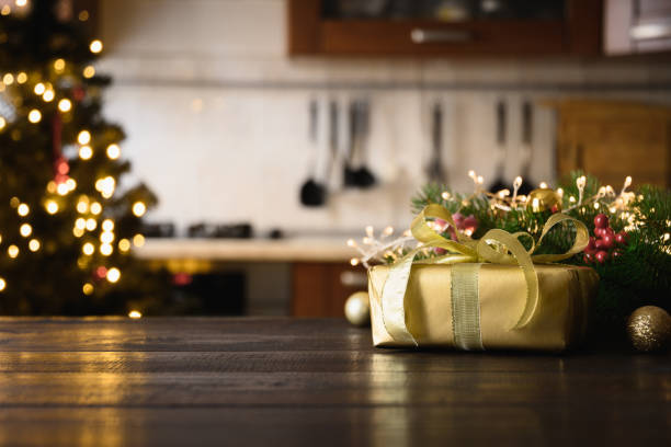 istock Wooden tabletop with gold gift Christmas decoration and blurred modern kitchen as background. 1284888572