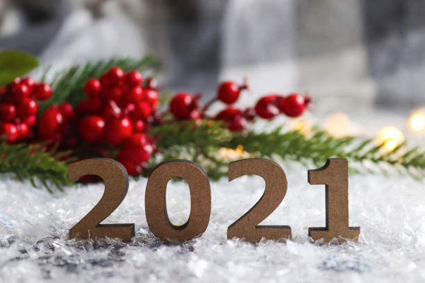 istock Numbers 2021 against a festive blurred background with Christmas tree and red berries. Beautiful New Year postcard. New Year's holiday background. Close up, selective focus 1284889333