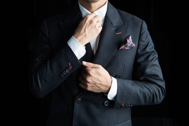 istock Asian businessman in a black suit is standing on a black background and has space for text. 1284889897