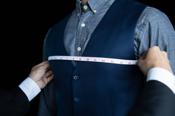 The dressmaker was measuring the chest width of a man wearing a blue suit. The dressmaker was measuring the chest width of a man wearing a blue suit. mens fashion stock pictures, royalty-free photos & images