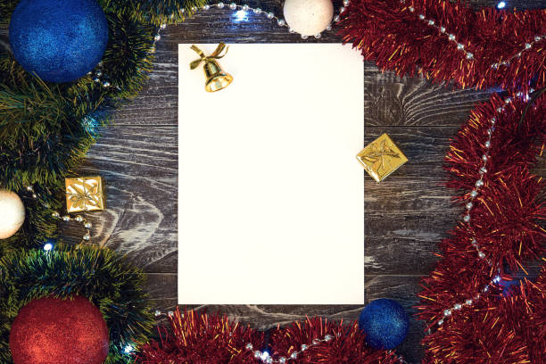 istock Vertical paper blank with christmas frame all aroud the frame. Flat lay. New year card gift. Balls, presents, snowballs, green and red tinsel. On grey wooden background. Top view. 1284890725