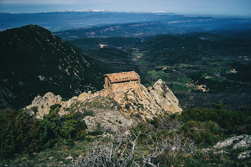 An old small stone house built on top of a rock on the heights with views of the mountains and fields
