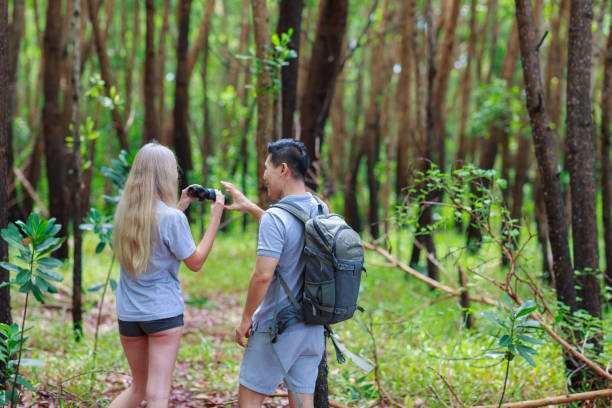 istock Young couple hiking trough forest and watching birds with binoculars. 1284893091