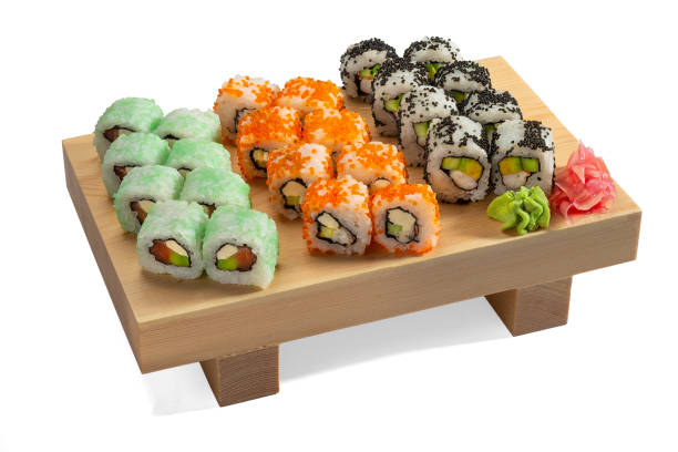 Sushi set and sushi rolls on a wooden board Fresh colorful Uramaki Sushi Rolls with rice, tofu, fried shrimp, cucumber, flying fish caviar and nori. Isolated on white background. sushi plate stock pictures, royalty-free photos & images