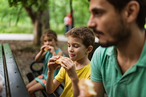 Single father with his kids having a picnic outdoors.