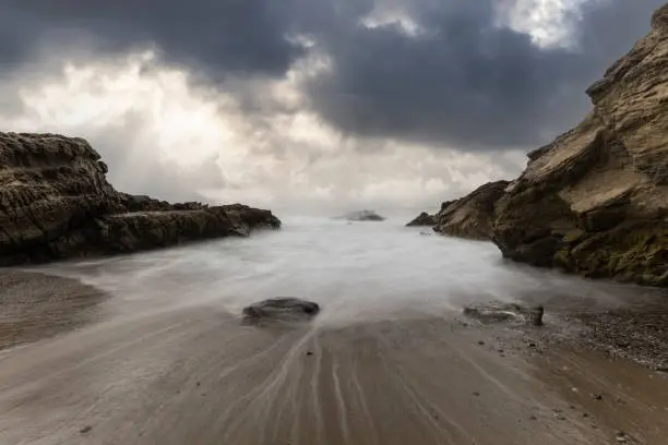 Rocky cove with motion blurred water and stormy sky at Leo Carrillo State Beach in Malibu, California.