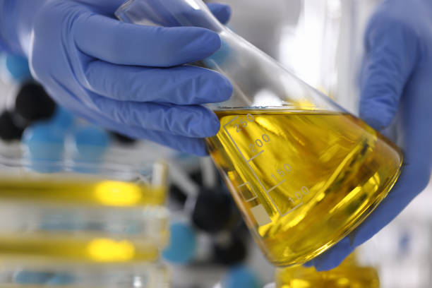 istock Gloved hands hold flask with golden liquid. 1284897435