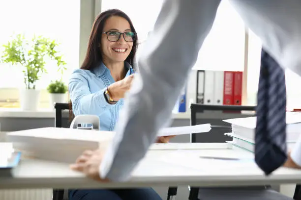Photo of Smiling woman at work table communicates with colleague