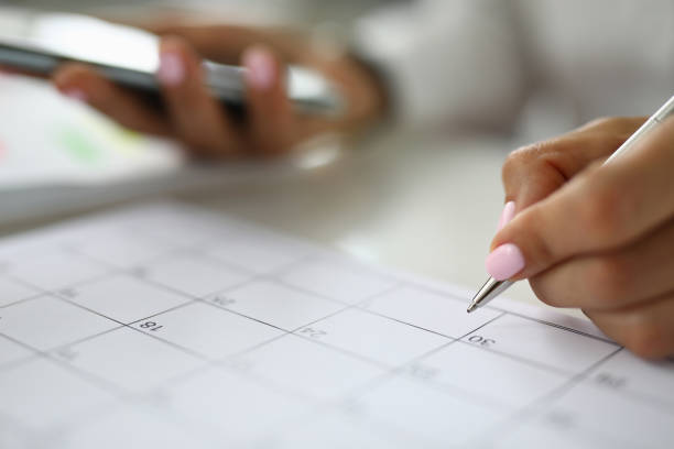 istock Woman's hand holds pen and marks calendar. 1284897573