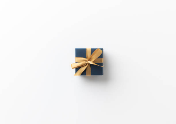 istock Top view blue present gift box with gold ribbon on the white table background. Merry christmas and Happy new year theme. 1284898741
