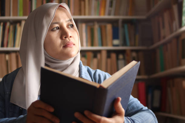 istock Asian muslim woman thinking while reading book, education concept, learning studying in library 1284898982