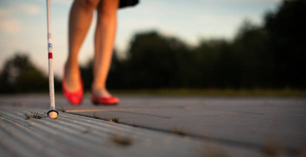 Blind woman walking on city streets, using her white cane to navigate the urban space better and to get to her destination safely