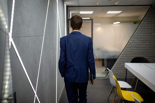 Young businessman walks out of the conference room, back view