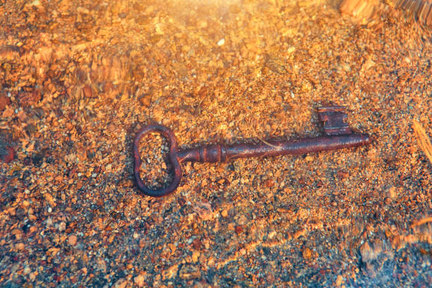 o mar apareceu na praia de areia uma velha chave vintage para um baú de tesouros. o conceito de sucesso, sorte e riqueza - treasure luck treasure chest wealth - fotografias e filmes do acervo